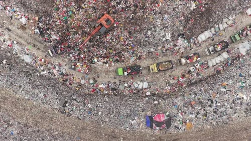 Aerial view of a huge landfill with excavator and trucks in bali