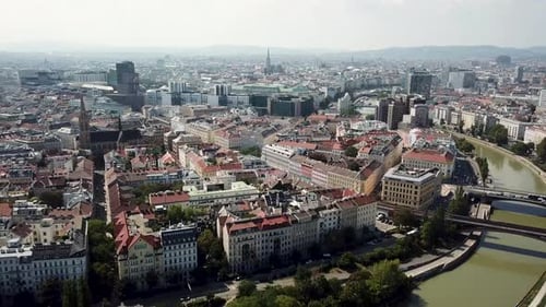 Aerial flyover shot of Vienna City with colorful houses and apartment buildings beside river. Histor
