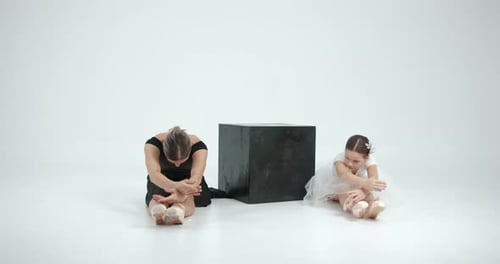 Pequeña bailarina con profesor posando en un estudio blanco