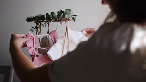 Woman Arranging Adorable Baby Clothes on Rack