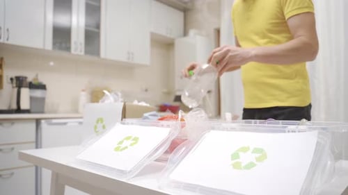 Person throwing waste into recycling bins in the kitchen.