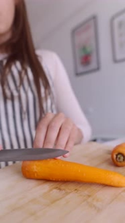 Woman Slicing Carrot on Wooden Cutting Board
