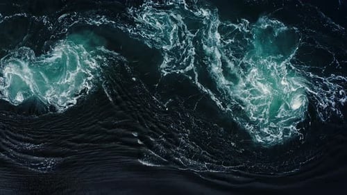 Waves of the Sea Water Meet with Underwater Pointed Rocks Forming Whirlpools