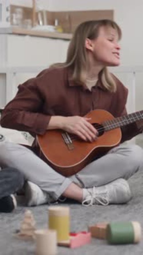 Woman Plays Ukulele and Sings While Sitting Down