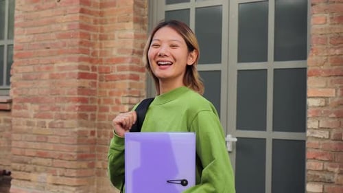 Smiling young woman stands outside of brick building