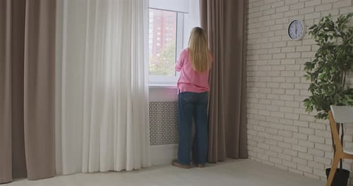 Eine Frau stellt Rollläden an einem Fenster zu Hause ein