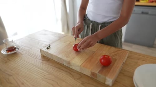 Young Woman Cutting Tomato on a Cutting Board
