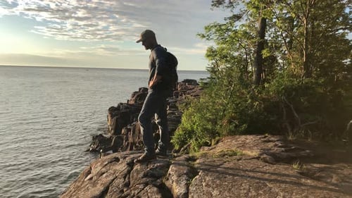 Man, ocean and hiking on cliff with travel, view with nature and environment