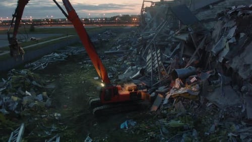 Excavator Operates at Demolition of Sports Stadium at Dusk