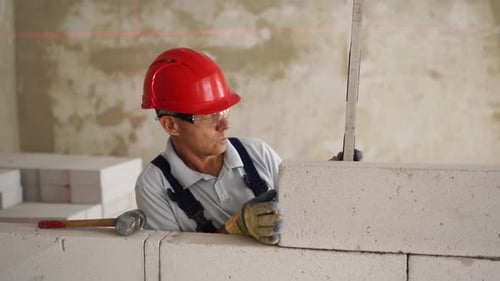 Bricklayer Using Rubber Mallet Hammer to Tap and Level Concrete Blocks Wall Contractor Uses Precise
