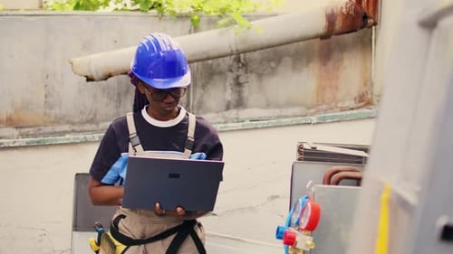 Woman Technician Using Laptop Inspecting AC Unit