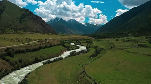 River Running Through a Lush Green Valley Surrounded By Mountains and a Lush Green Valley