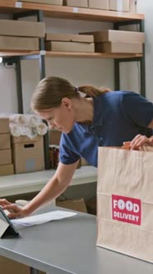 Vertical of Female Employee Packing Takeaway Groceries Order at Dark Store