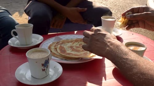 Em um restaurante local de dhaba, um grupo de amigos tomando café da manhã com chá e parathas.