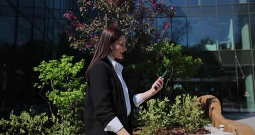 Business Woman on Video Call Walks Past Modern Building