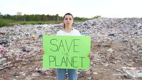 Woman Holding Save the Planet Sign at Landfill