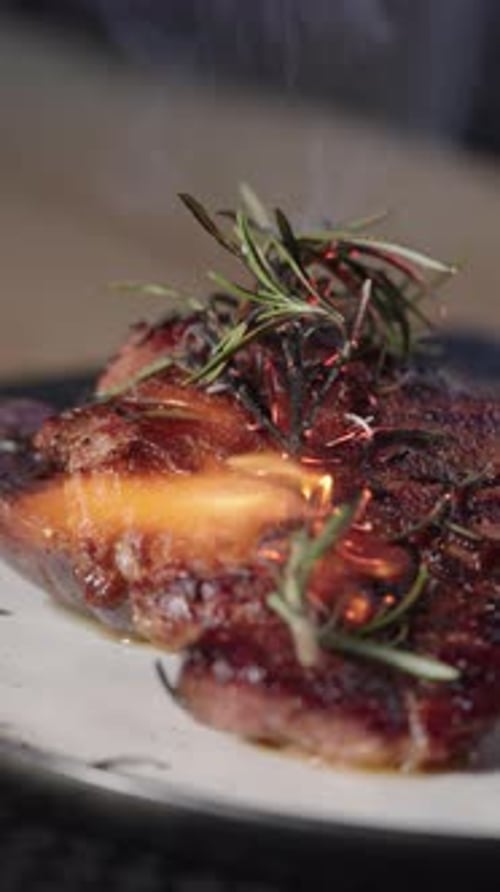 Delicious steak with rosemary being torched on plate