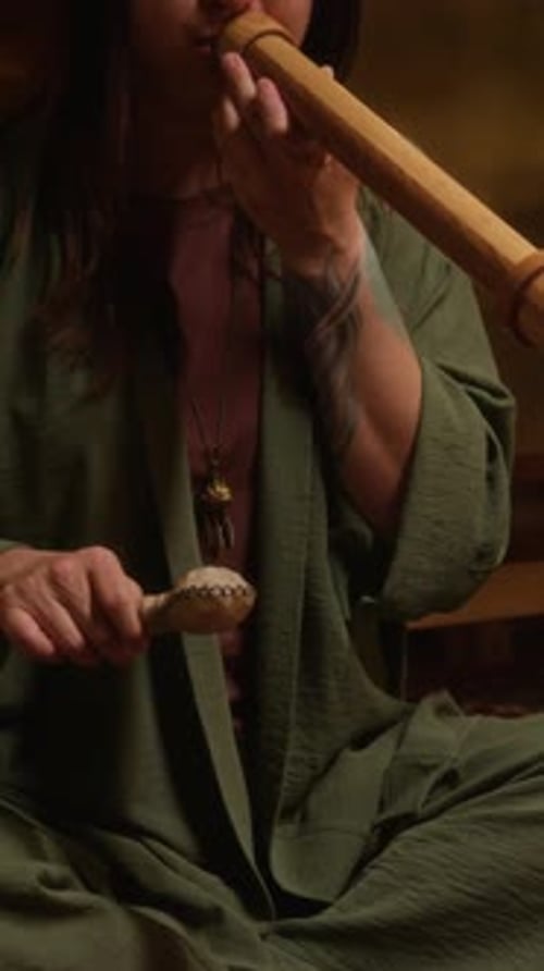 Woman plays flute in a dimly lit room