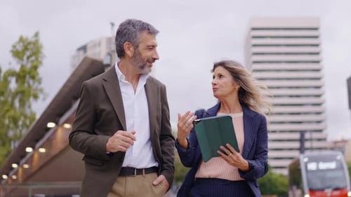Business Professionals Discuss Work While Walking Outdoors