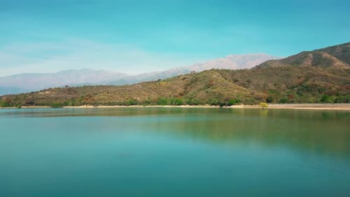 Aerial drone flying over a blue water lake with mountains landscape
