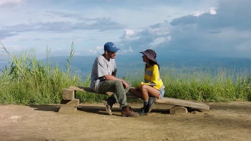 Young Couple Conversing on Bench Overlooking Landscape