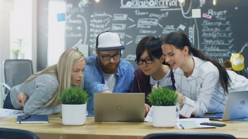 Creative Team Collaborating on Laptop in Modern Office