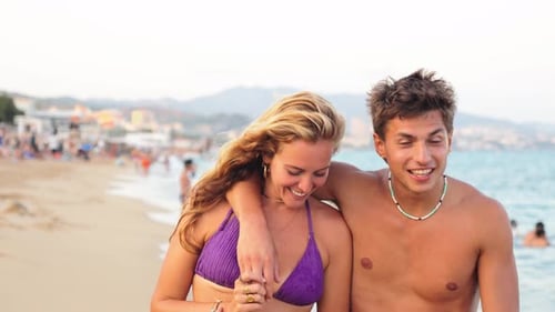 Joyful Couple Walking Hand in Hand Along the Serene Beach Enjoying a Sunny Day By the Ocean Waves