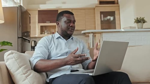 Professional Man Video Conferencing at Home on Laptop