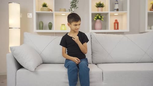 Boy Itching, Sitting on Couch in Home