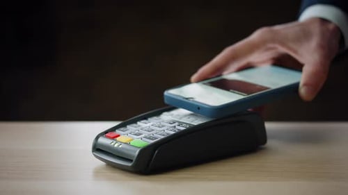Cashless Payment Using Smartphone on Modern Bank Terminal Indoors Close Up