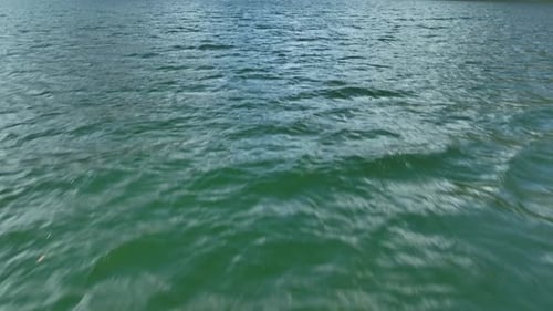 Gentle waves ripple across emerald green water in an outdoor natural setting