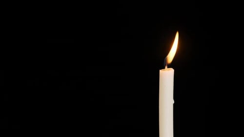 One Candle Burning and Extinguished on a Black Background Copy Space