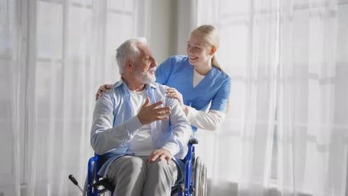 Kind Caregiver Talking With a Senior in Wheelchair