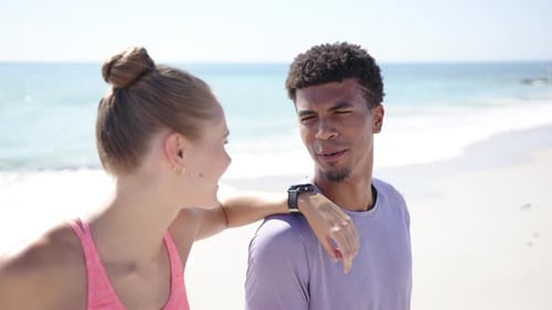 Young Caucasian woman and biracial man share a joyful moment on a sunny beach
