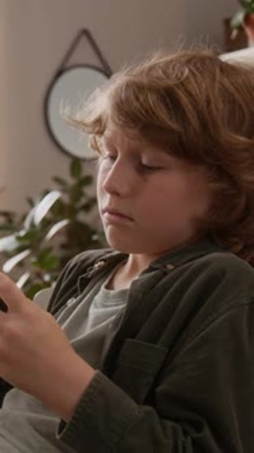 Vertical of Boy Using Phone and Getting Distracted by Conversations around