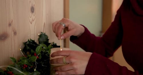Woman Lights Christmas Candles for Holiday Celebration