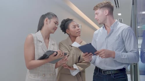 Multi-ethnic business staffs stand and discuss in the walk way of office about their project