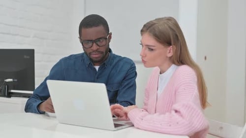Coworkers Collaborating on Laptop in Modern Office