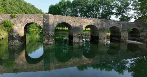 Schöne alte Steinbrücke, die sich im Fluss spiegelt.