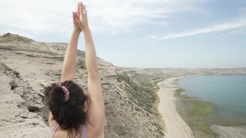Back View Of Young Woman Doing Warm-up Yoga Pose on beautiful ocean landscape location - Zoom in