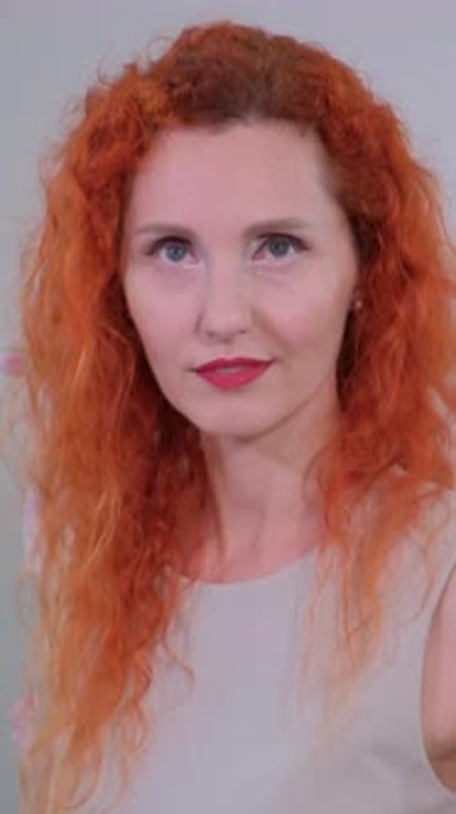 Portrait d'une belle femme aux cheveux roux éclatants élégamment vêtue d'une tenue neutre