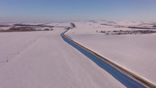 The Car Drives Along the Road Among the Snowcovered Fields in Winter Aerial Photography of the
