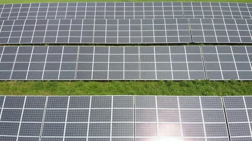 Aerial pan over photovoltaic solar panels at a power plant.