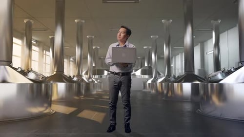 Asia Male Worker Use Laptop And Looks Around at Beer Plant