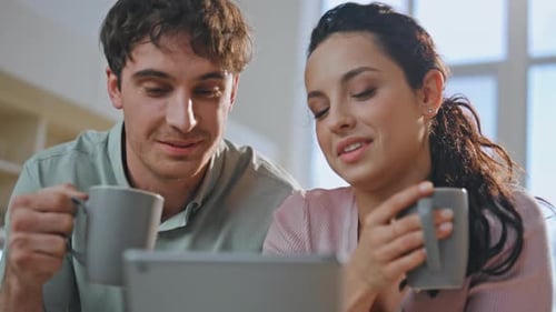 Smiling Spouses Drinking Coffee Looking Tablet in Kitchen Close Up Happy Family