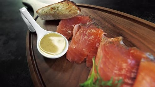 Nahaufnahme entlang eines Holzbretts mit geräuchertem Lachs und einem Stück Brot mit Olivenöl