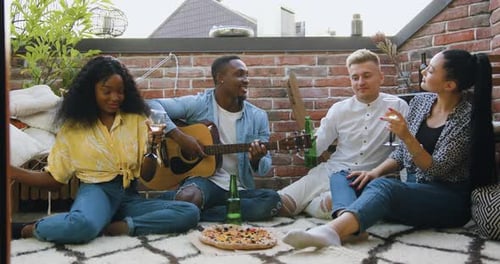 Attractive multiracial friends celebrating summer party in the terrace with songs beverages