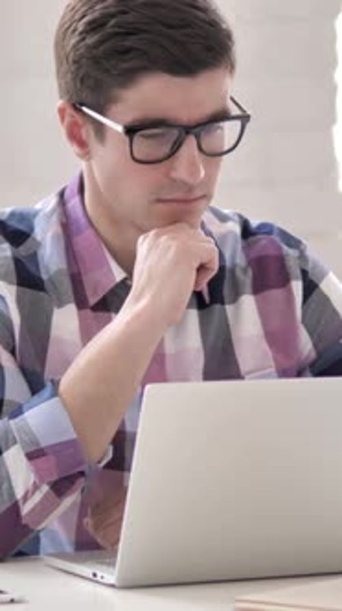 Young Man Working on Laptop Computer at Desk