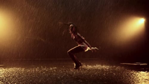 Energetic Freestyle Dance In Heavy Rain With Bold Orange Illumination