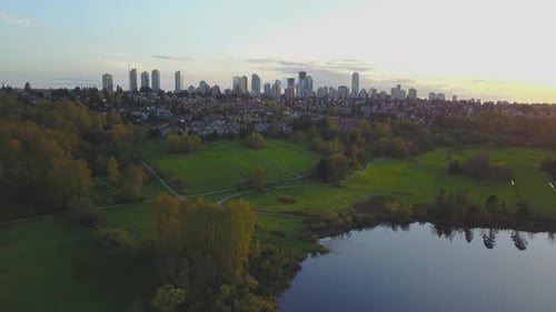 Aerial Footage of a Lake in the City Park During a Colorful and Vibrant Sunset with Red Color Sky